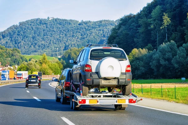 スロベニアのアスファルト道路に新しい車両を搭載したトレーラーを運ぶ車 — ストック写真