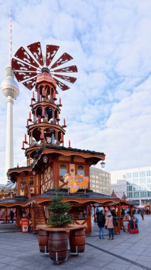 Berlin, Almanya - 10 Aralık 2017: Berlin, Kış Almanya'sında Alexanderplatz'daki Noel Pazarı'nda Fernsehturm ve Christmas Carousel'de insanlar. Advent Fuar Dekorasyon ve El Sanatları Öğeleri ile Tezgahları
