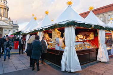 Berlin, Almanya - 8 Aralık 2017: Almanya'nın Kış Berlin kentinde Gendarmenmarkt'taki Gece Noel Pazarı'nda yiyecek Tezgahlarında İnsanlar. Advent Fuarı Dekorasyon ve El Sanatları Çarşısı'ndaki Ürünler.