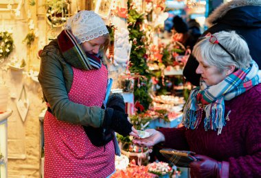 Berlin, Almanya - 8 Aralık 2017: Winter Berlin, Almanya'daki Gendarmenmarkt'ta Gece Noel Pazarı'nda Noel Süsleri satın alan bir müşteriye nakit değişim veren trader.