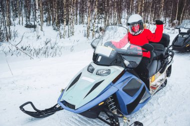 Woman in Snowmobile in Winter Finland, Lapland at Christmas. Extreme Sport Activity and Recreation in Cold Season. Drive a Snow Mobile Vehicle If you like Speed, Ice and Fun. clipart