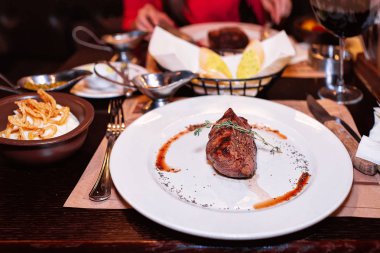 Orta az pişmiş biftek bir restoranda beyaz tabakta biber sosu ile