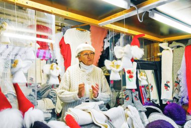 Riga, Letonya - 25 Aralık 2015: kışın, Letonya Riga'da Noel Pazar tezgahları örme giysiler satan kadın kıdemli.