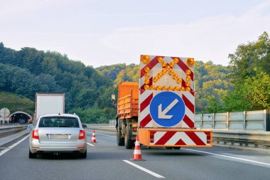 Sol yansıtıcı yön yol işareti aşağı ok karayolu Polonya taşıyan kamyon.
