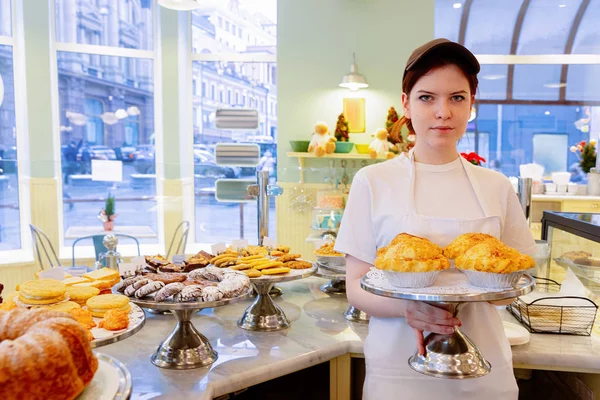 Giovane ragazza panettiere con torte in grembiule in panetteria — Foto Stock