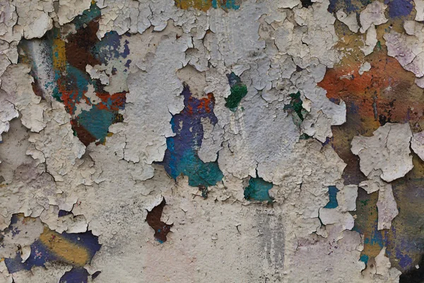 An old plastered wall with many layers of peeling colorful paint