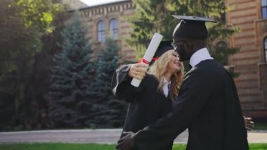 Erkek ve kadın geleneksel elbiseler mezuniyet töreninde sarılma karışık ırkların onların University yakınındaki. Grup öğrencilerimiz. Açık