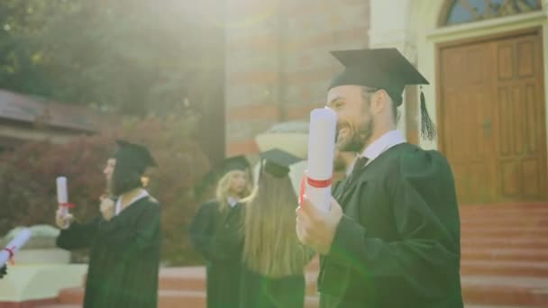 Jóképű férfi diplomás átölelve az apjával, apa fiára egy érettségi Egyetem gratulált. Kültéri — Stock videók