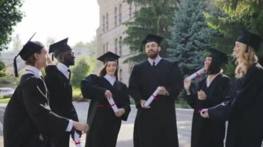Grup oof çok etnik ve mezunları önlük ve kapaklar onların diploma Üniversite Binası yakınındaki savurma. Açık havada