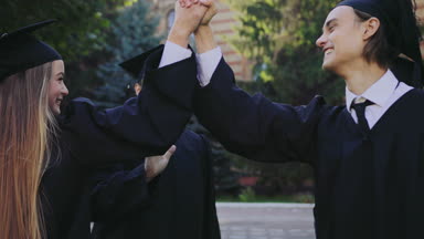 Mezuniyetten sonra birbirlerine beşli veren diploma ile genç mutlu mezunları da üniversite bina yakınındaki. Açık