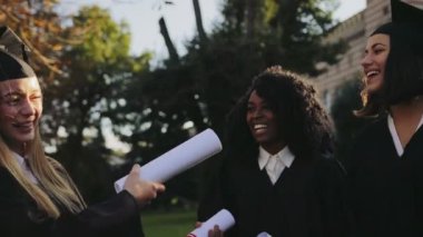 Siyah önlük ve eğleniyor ve onların Üniversite binası parkta gülüyor kapaklar kadın mezunlarının kapatın. Açık havada