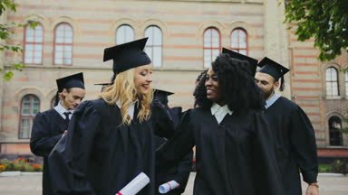Mutlu karışık ırklar mezunlarının mezuniyet töreninden sonra Üniversite Binası yakınındaki elinde diploma ile yürüme gülümsedi. Açık