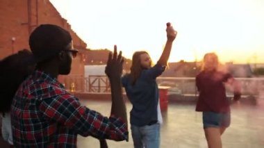 Kentsel alanda çatı partide pembe duman el bombası ile çalışan genç karışık koştu arkadaşlar. Gün batımı arka plan. Dışarıda.