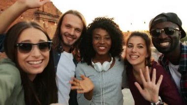 Selfie yapım ve çatı partide kamera ellerini sallayarak multiethnical arkadaşlar. Kentsel. Gün batımı arka plan. Dışarıda.