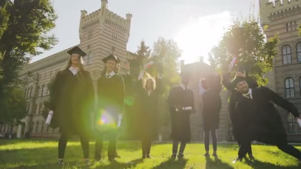 一群多 etnical 的男女毕业生, 在快乐的毕业典礼上, 穿着传统的衣服, 手里拿着毕业证书。户外 — 图库视频影像