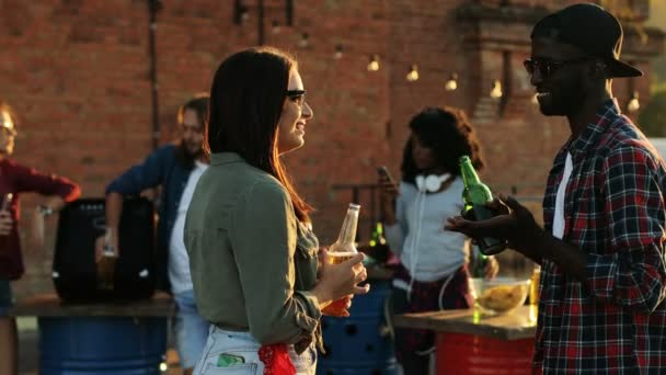 Female and male friends chatting and drinking beer at the rooftop party. The brick wall and urban space background. Outside. Mixed races — Stock Video