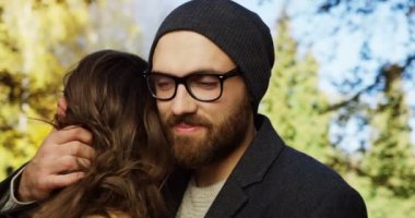 Genç romantik sevimli çift şefkatle sarılma sevgi ve kafasını yaslanmış kadının omuz parkta bir güneşli ama serin günde mans. Erken sonbahar. Portre vurdu. Yakın çekim. Açık