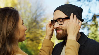 Canlı birbirine bakarak ve gülümseyen güzel genç çiftin yakın çekim. Sabitleme kadın bir şapka mans. Erken sonbahar parkta. Güneşli bir gün. Açık. Portre
