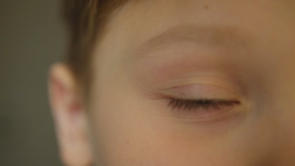 Close up of the boys half face. Cute blonde boy blinking to the camera. Portrait shot. Indoors. — Stock Video