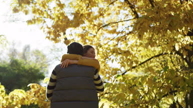Pitoresk parkta sarı ağaçların altında dönen genç mutlu çift. Sonbahar güneşli havalarda. Açık havada