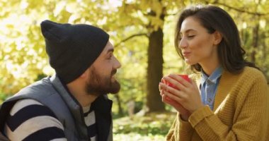 Pitoresk park ve kırmızı bardaktan sıcak çay içme kadın oturuyor ve aşık çekici genç çiftin yakın çekim. Güneşli Güz. Dışarıda. Portre vurdu
