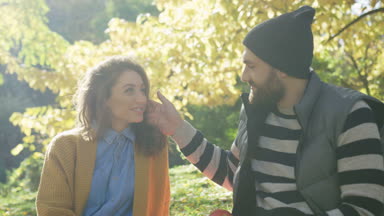 Romantik Çift sonbaharda güneşli bir parkta otururken okşama yakın çekim. Portre vurdu. Dışarıda