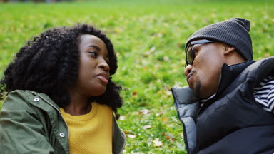 Çim üzerinde yalan ve pitoresk parkta sonbaharda sohbet Afro-Amerikan çift çekici genç portresi. Güneşli bir gün. Açık. Yakın çekim