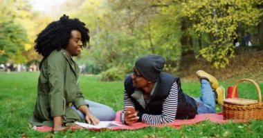 Afrika kökenli Amerikalı çift parkta zaman harcama. Onun yanında yatan bir kitap ve genç adam ile oturan bir genç bayan. Sonbahar günü. Açık havada