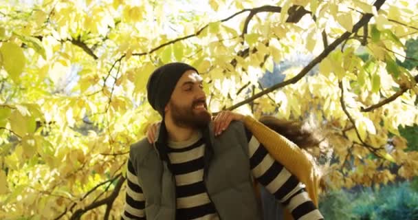 Close up of young joyful couple having fun in the yellow park. Woman jumping on the mans back. Sunny fall. Outdoors — Stock Video