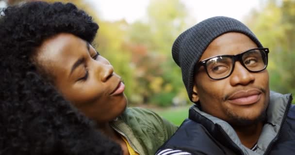 Primer plano de la joven pareja afroamericana encantadora enamorada abrazando y riendo sinceramente a la cámara en el parque en el otoño. Al aire libre. Retrato — Vídeos de Stock