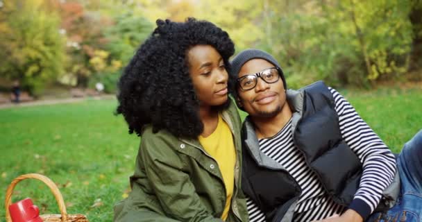 Retrato de una joven pareja afroamericana enamorada sentada en el picnic y sonriendo. Día soleado en el parque en otoño. Afuera. — Vídeos de Stock