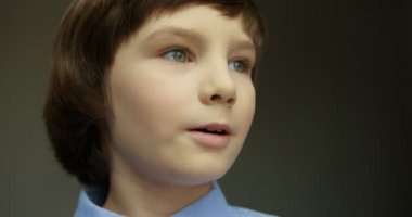 Mavi tişörtlü şirin çocuğun yakın portresi kameraya bakıyor ve gülümsüyor..