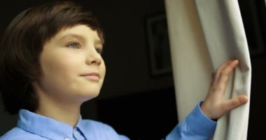 Küçük çocuk pencereye geliyor dışında arıyorsunuz, perdenin açılması portresi. Yakın çekim.