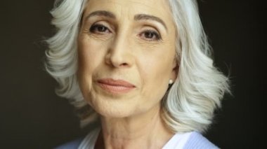 Torna ve kameraya gülümseyen mutlu yaşlı kadın portresi kapatın. Kapalı atış.