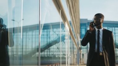 Yakışıklı genç Afro-Amerikan ofis çalışanı bir takım elbise ve kravat yavaş yavaş bir kentsel Cam ofis merkezi yürüyüş ve akıllı telefonda konuşurken. Adam sabah ofisine gidiyor. Açık havada