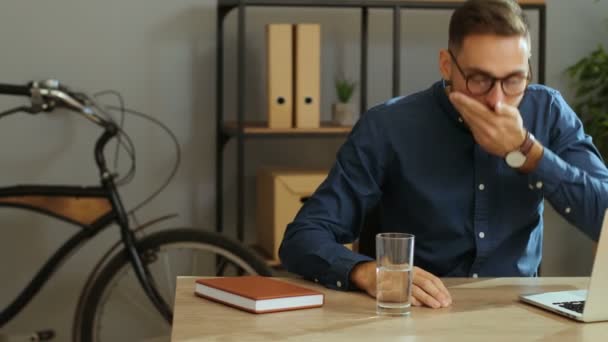 Tineri om de afaceri bolnav în ochelari elegant luând pilula în timpul timpului de lucru în biroul modern. Luând medecină — Videoclip de stoc