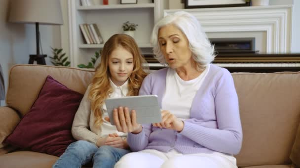 Close-up shot van mooie grootmoeder met haar kleinkinderen met behulp van Tablet PC zittend op de Bank thuis in de woonkamer. — Stockvideo