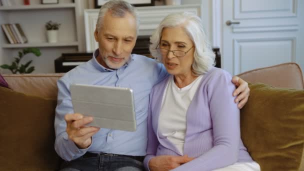 Gros plan des grands-parents heureux utilisant la tablette pour prendre selfie tout en étant assis sur le canapé à la maison . — Video