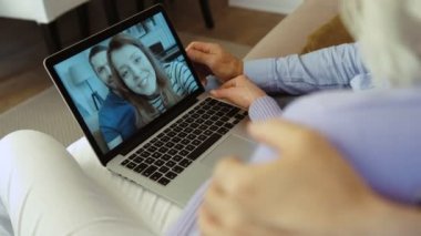 Yaşlı çiftin evde çocuklarla görüntülü konuşma yapmak için dizüstü bilgisayar kullanırken yakın plan çekimleri..