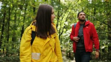 Sırt çantaları ve dürbün içinde görünen adam ile yeşil orman gezici genç çekici çift. Dışarıda