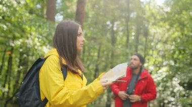 Genç kadın ve adam seyir için yol haritası ve Dürbün yardımıyla sırt çantaları ile. Getting kayıp. Açık havada
