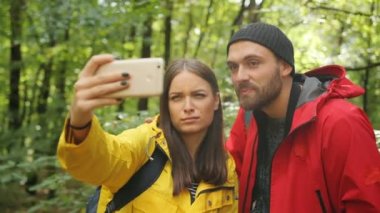 Genç tatlı çift ormanda komik selfies akıllı telefon ve grimasing yapma. Açık