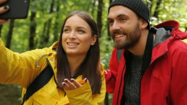 Ormanın ortasında akıllı telefonda görüntülü sohbet sahip genç güzel sportif çift. Adam yapması. Dışarıda