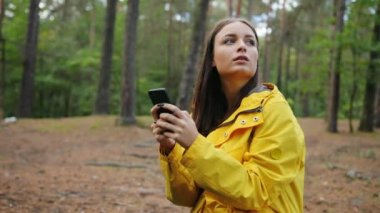 Ormanın ortasında ayakta, ona akıllı telefon kayıt ve etrafa sevimli genç kadın. Açık