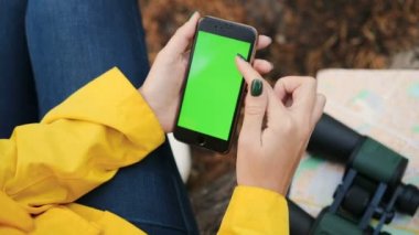 Üstten görünüm kaydırma ve yakınlaştırma ormanın içinde siyah akıllı telefon ekranında el üzerinde. Harita ve dürbün üzerinde arka plan bulanık. Yeşil ekran. Chroma anahtar. Açık. Yakın çekim