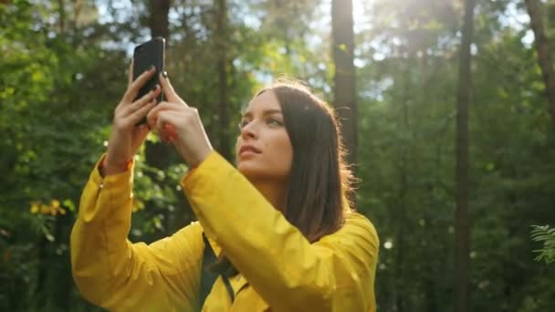 Portrait de jeune jolie femme prenant des photos de la nature sur le smartphone noir lors d'une randonnée en forêt. Journée ensoleillée. Extérieur 