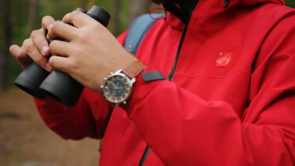 Close up of the appealing young man rising his hands with binoculars and looking in the binoculars in the forest. Outside. Portrait — Stock Video