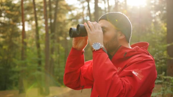 Close up of the young sporty man looking in the binoculars and than smiling into the camera in the sunlight in the forest. Outdoors. Portrait shot — Stock Video