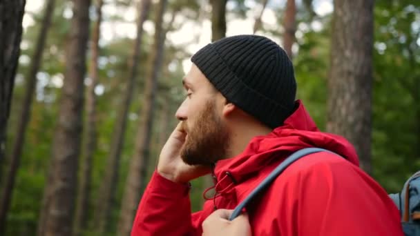 Primo piano dell'attraente uomo caucasico col cappello che parla al cellulare nella foresta. Ritratto. All'aperto — Video Stock