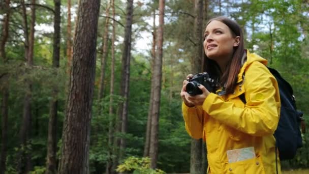 Jeune jolie femme marchant seule dans la forêt et prenant des photos de la nature sur l'appareil photo vintage. Extérieur — Video